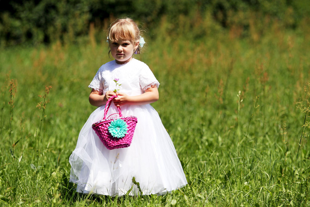 Fotografia dziewczynki w białej sukience zbierającej kwiatki na łące autorstwa Ani Wilanowskiej.