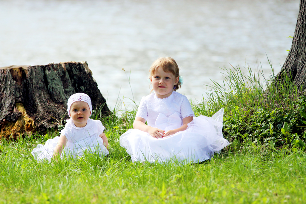 Fotografia dziewczynek w białych sukienkach na trawie autorstwa Ani Wilanowskiej.
