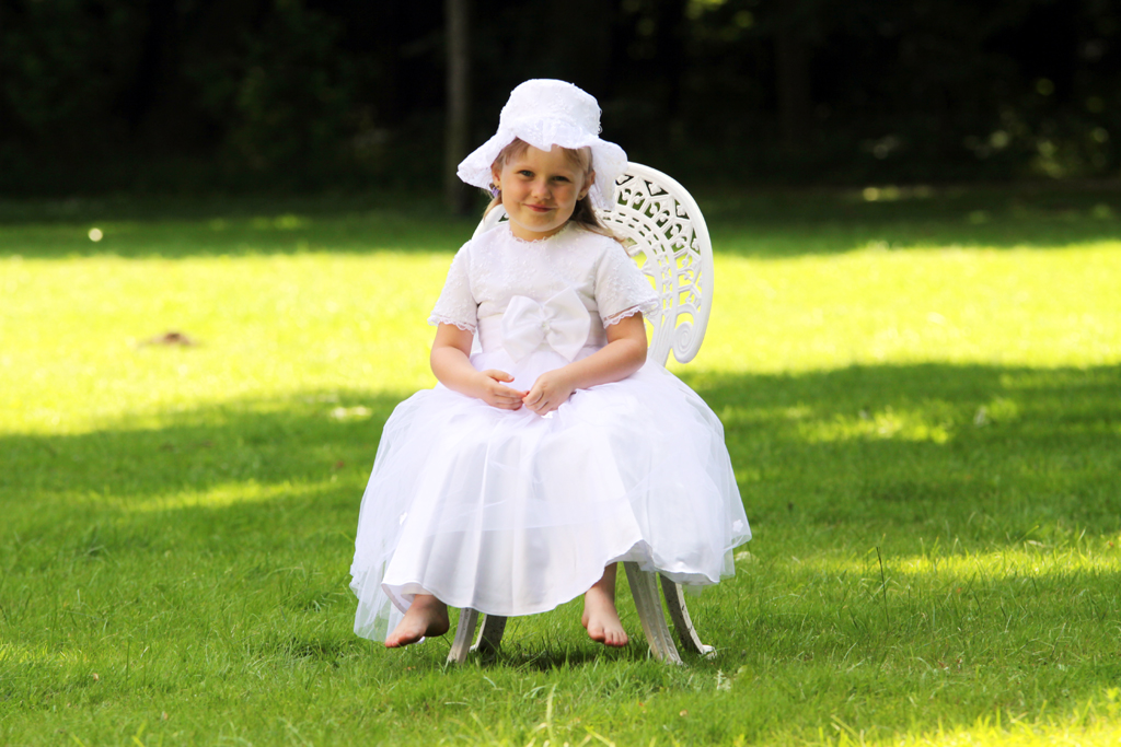 Fotografia dziewczynki w białej sukience na krześle na trawie autorstwa Ani Wilanowskiej.