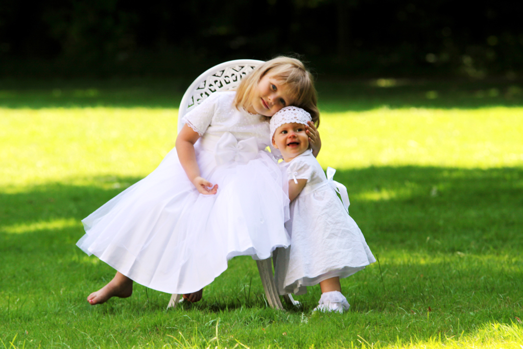 Fotografia dziewczynek w białych sukienkach na trawie autorstwa Ani Wilanowskiej.