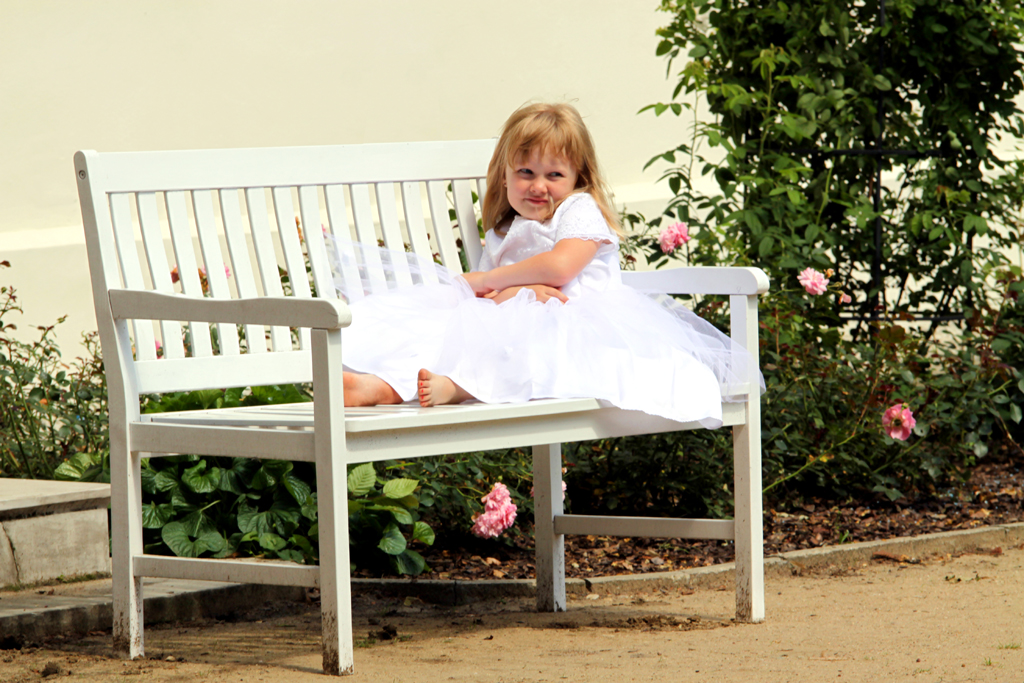 Fotografia dziewczynki w białej sukience na ławce autorstwa Ani Wilanowskiej.