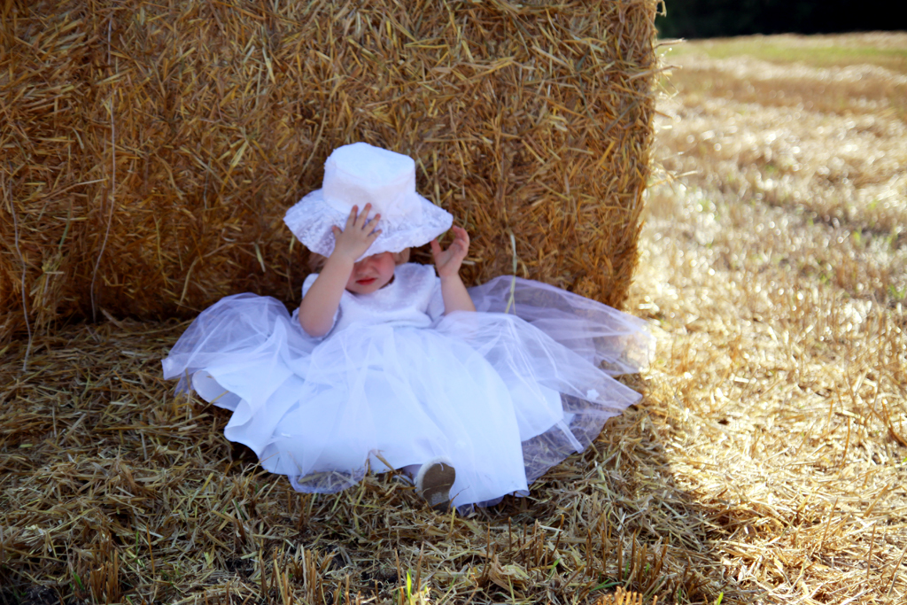 Fotografia dziewczynki w białej sukience na sianie autorstwa Ani Wilanowskiej.