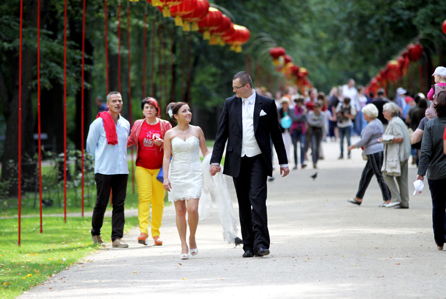 Fotografia młodej pary idącej chodnikiem wykonana w Łazienkach podczas sesji poślubnej autorstwa Ani Wilanowskiej.