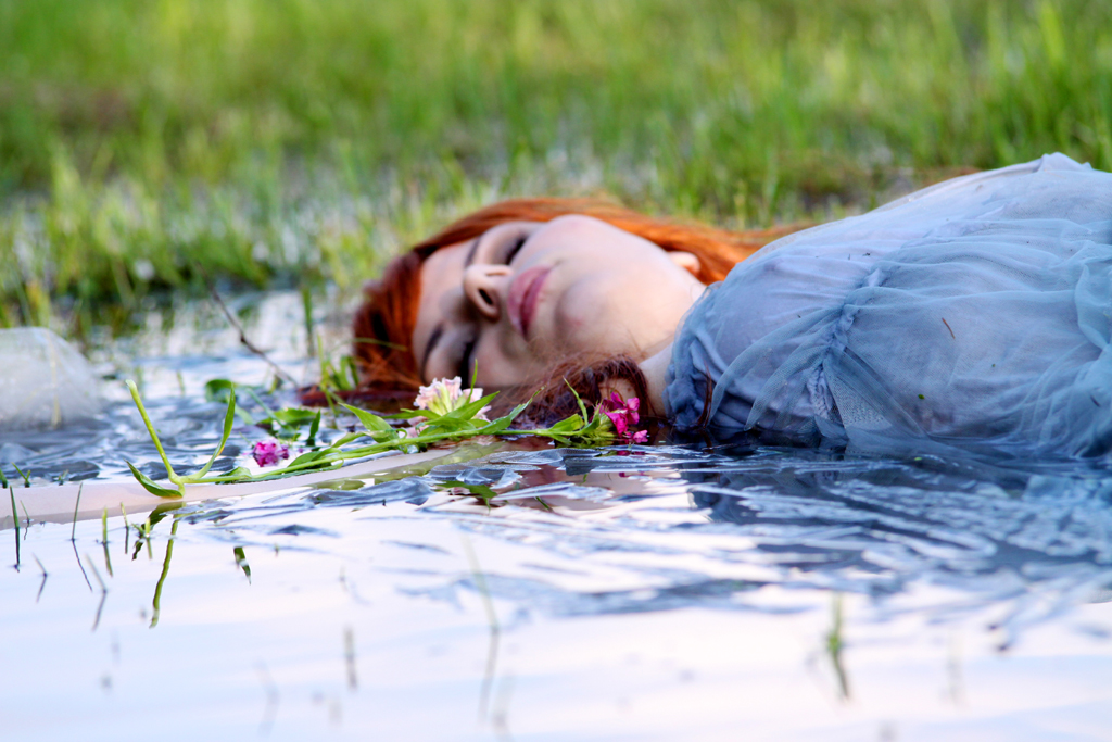 Fotografia kobiety leżącej w wodzie na łące autorstwa Ani Wilanowskiej.