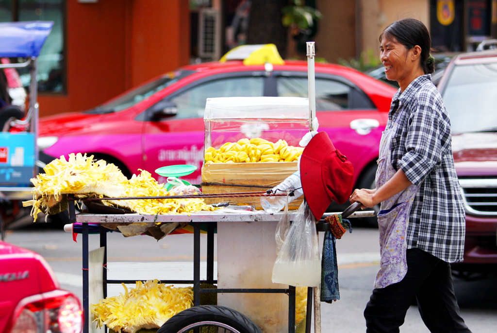 Fotografia kobiety sprzedającej jedzenie zrobiona na ulicy w Bangkoku podczas podróży do Tajlandii. Autorstwa Ani Wilanowskiej.