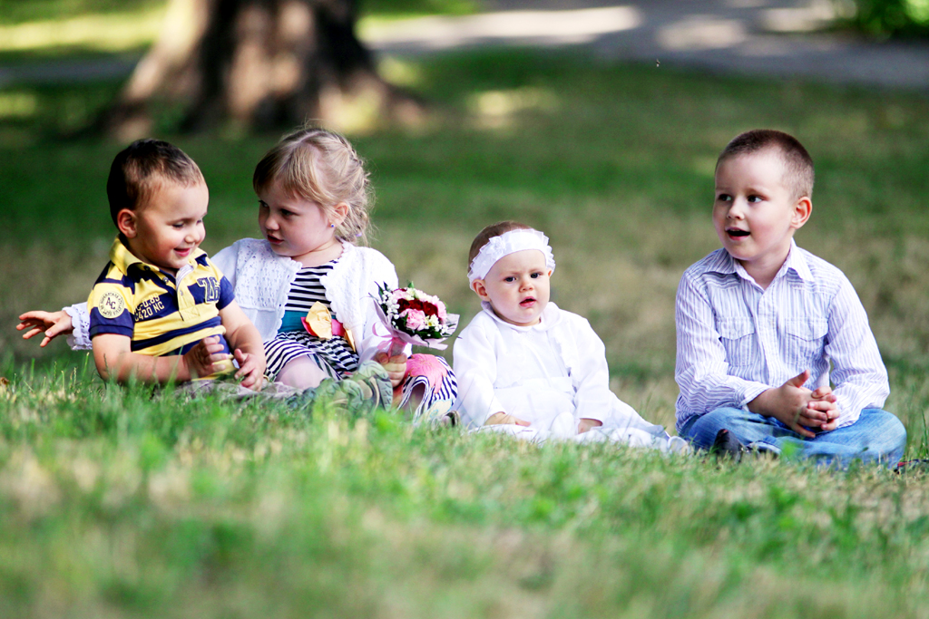 Fotografia dzieci siedzących na trawie autorstwa Ani Wilanowskiej.