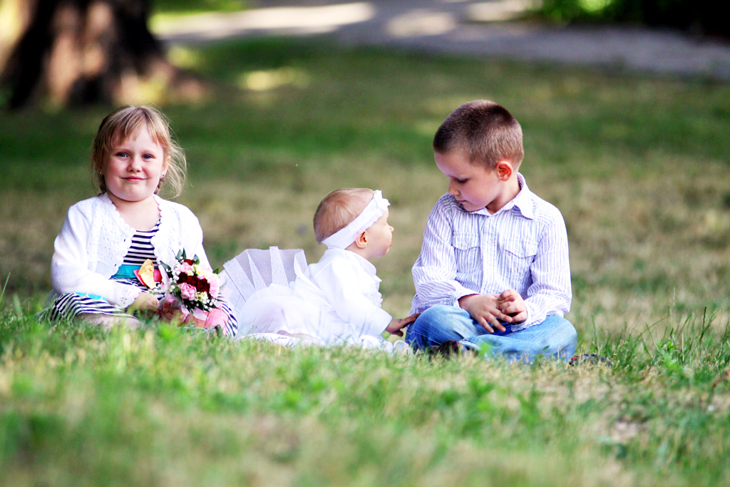 Fotografia dzieci siedzących na trawie autorstwa Ani Wilanowskiej.