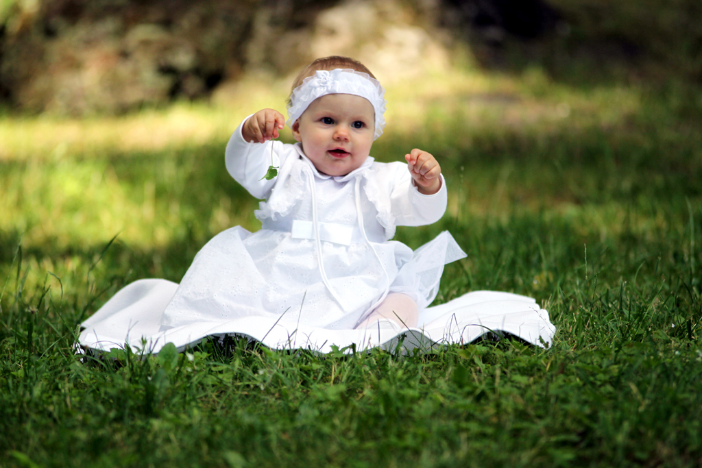 Fotografia dziewczynki w białej sukience wykonana na trawie autorstwa Ani Wilanowskiej.