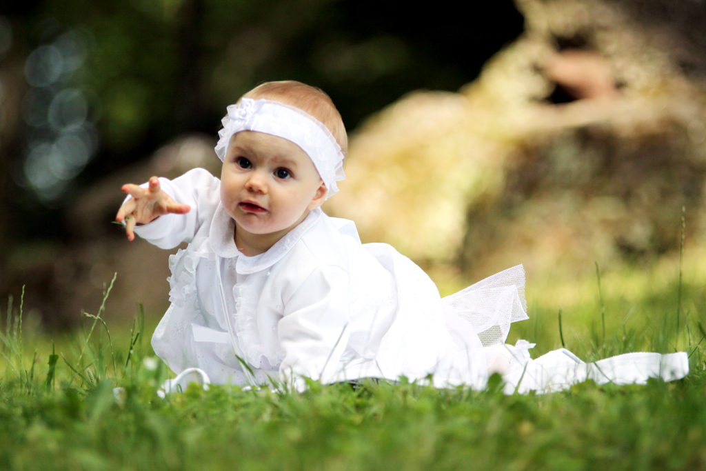 Fotografia dziewczynki w białej sukience wykonana na trawie autorstwa Ani Wilanowskiej.