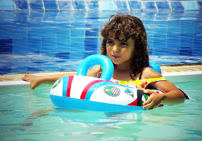 Fotografia dziewczynki z kołem ratunkowym w basenie autorstwa Ani Wilanowskiej. 