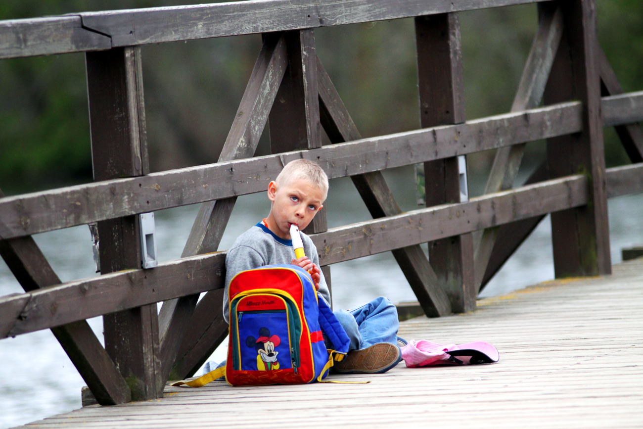 Fotografia chłopca grającego na flecie na moście autorstwa Ani Wilanowskiej. 