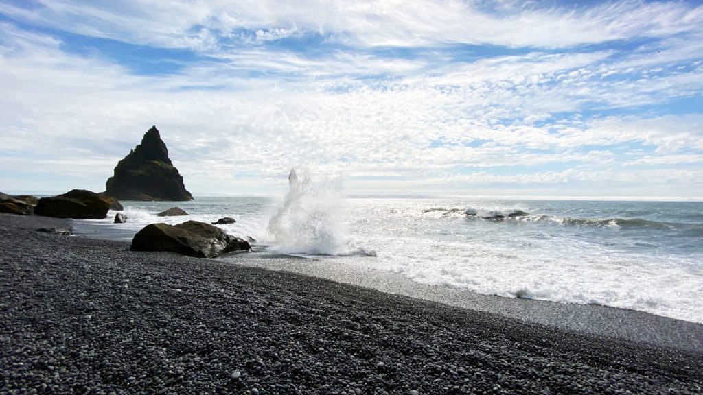 Fotografia fal uderząjących o kamienie na czarnej plaży Reynisfjara, zrobiona podczas podróży na IsLandię. Autorstwa Ani Wilanowskiej