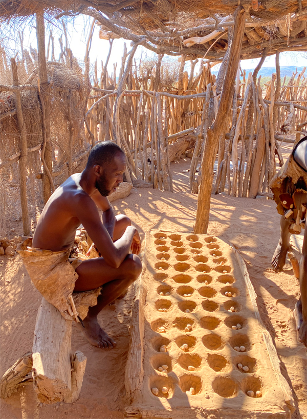 Fotografia mężczyzny grającego w grę Owela z plemienia Damara zrobiona w Damaraland w Namibii, autorstwa Ani Wilanowskiej