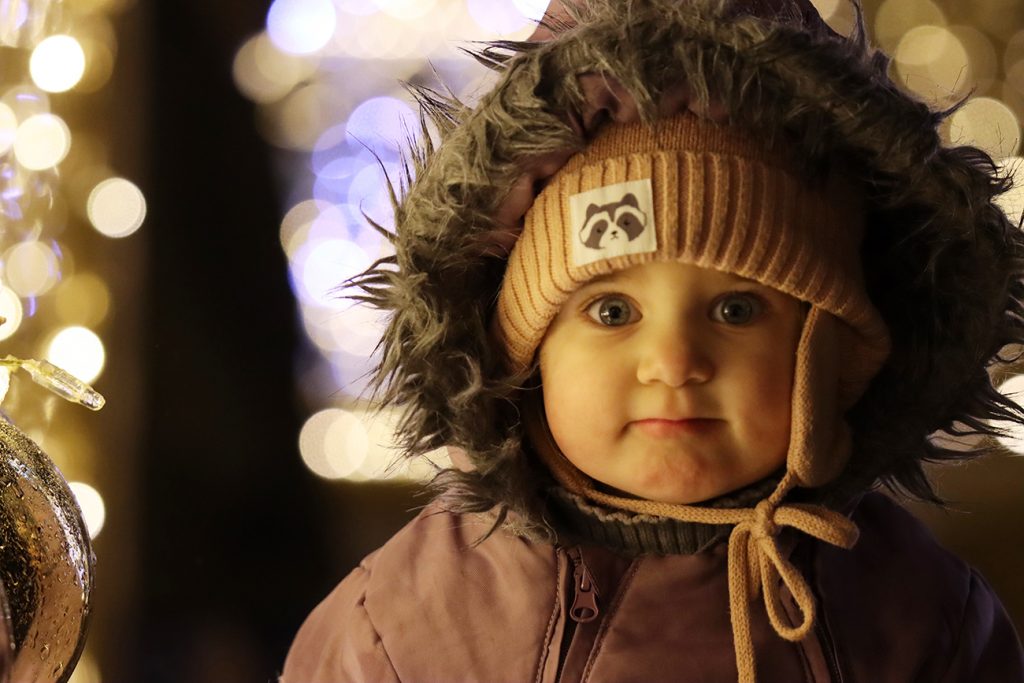 Zdjęcie dziewczynki zimą wśród ozdób świątecznych, autorstwa Ani Wilanowskiej