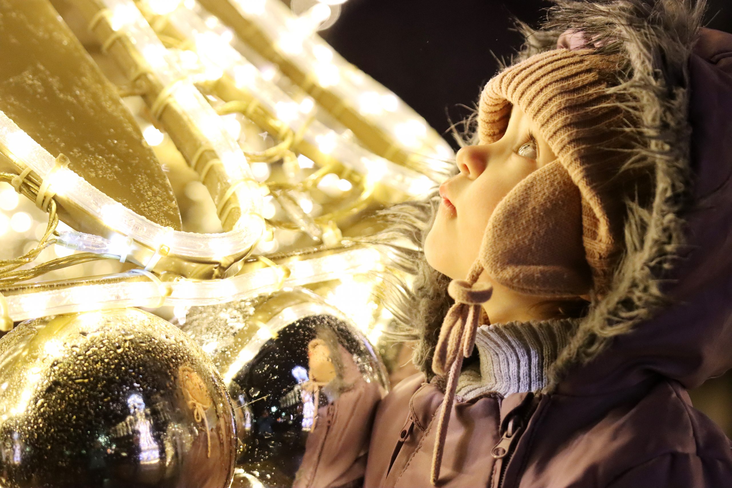 Zdjęcie dziewczynki zimą wśród ozdób świątecznych, autorstwa Ani Wilanowskiej