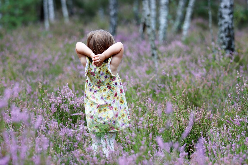 Zdjęcie dziewczynki w żółtej sukience w lesie, wśród wrzosów, autorstwa Ani Wilanowskiej