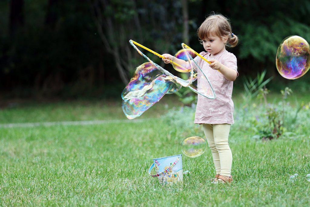 Zdjęcie dziewczynki latem bawiącej się bańkami, autorstwa Ani Wilanowskiej
