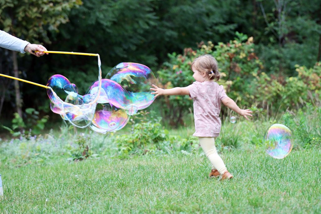 Zdjęcie dziewczynki latem bawiącej się bańkami, autorstwa Ani Wilanowskiej